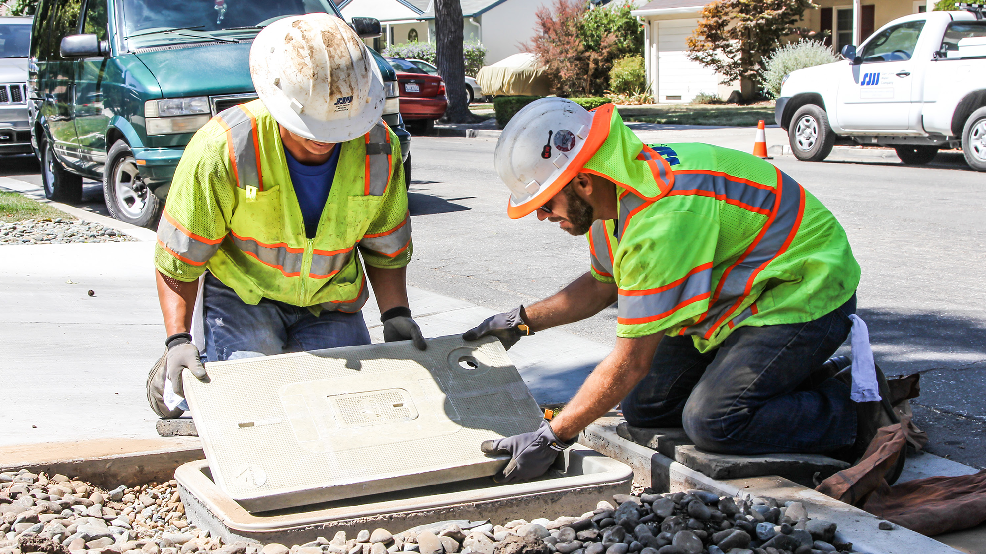 SJW workers covering a water shut off valve in front of a house